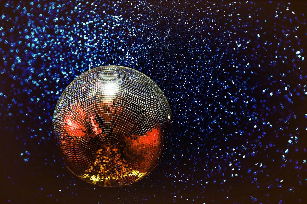 Shining disco ball with colorful reflections in a dark, starry background.